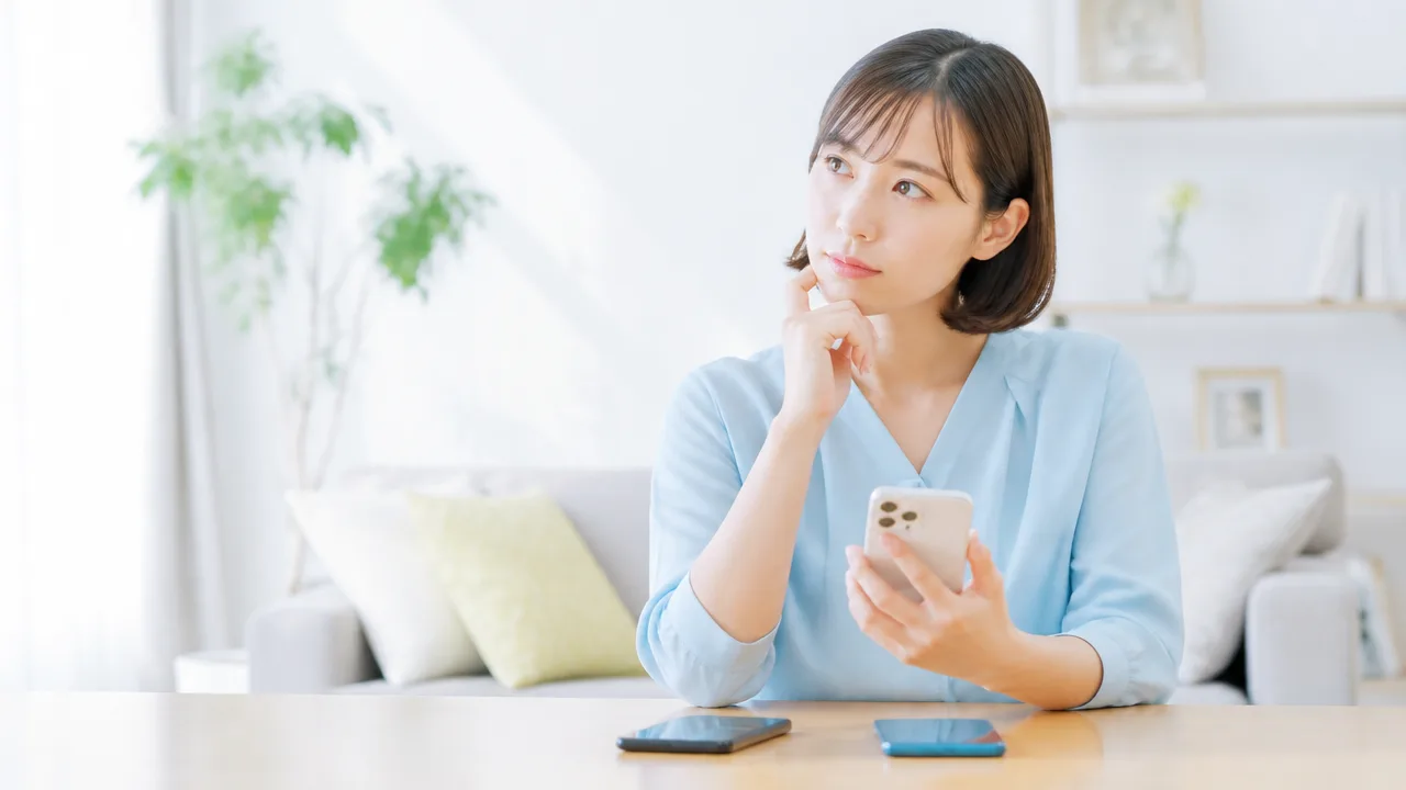 複数のスマホを前に、使う端末について考える人