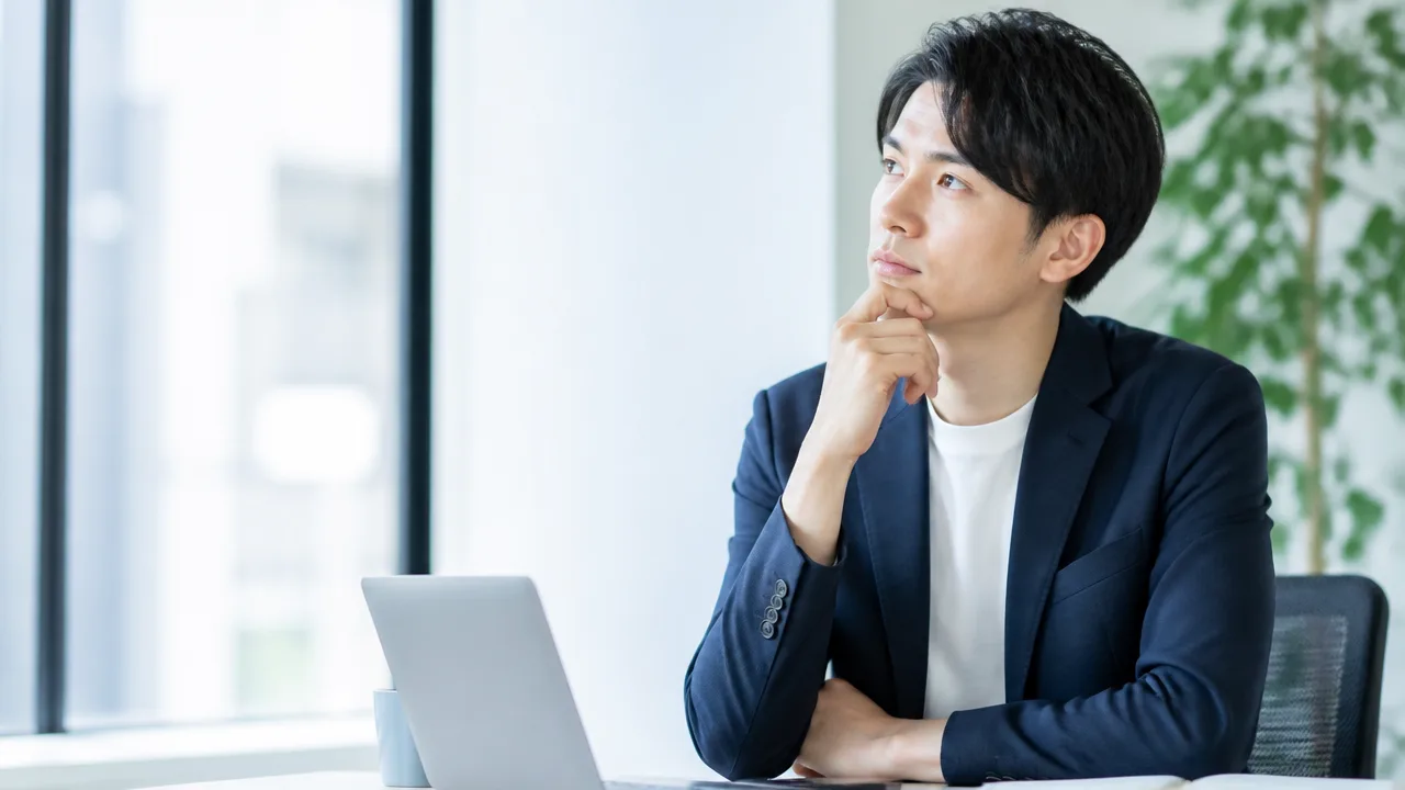 ノートパソコンを前に、勤務先の変更について考える人のイメージ