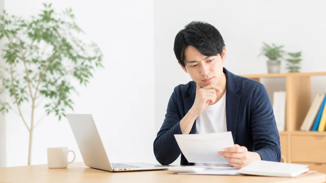 書類を手に取り、不動産の税金を確認する人のイメージ