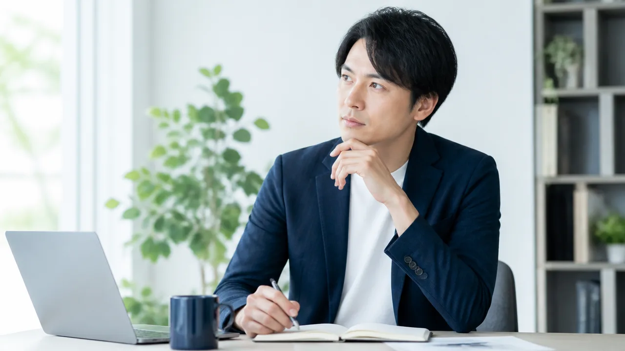 ノートパソコンの前で、働き方について考える人のイメージ