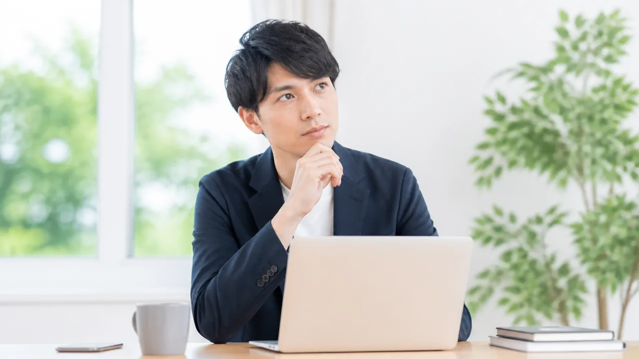 ノートパソコンを前に会社の肩書について考える人のイメージ