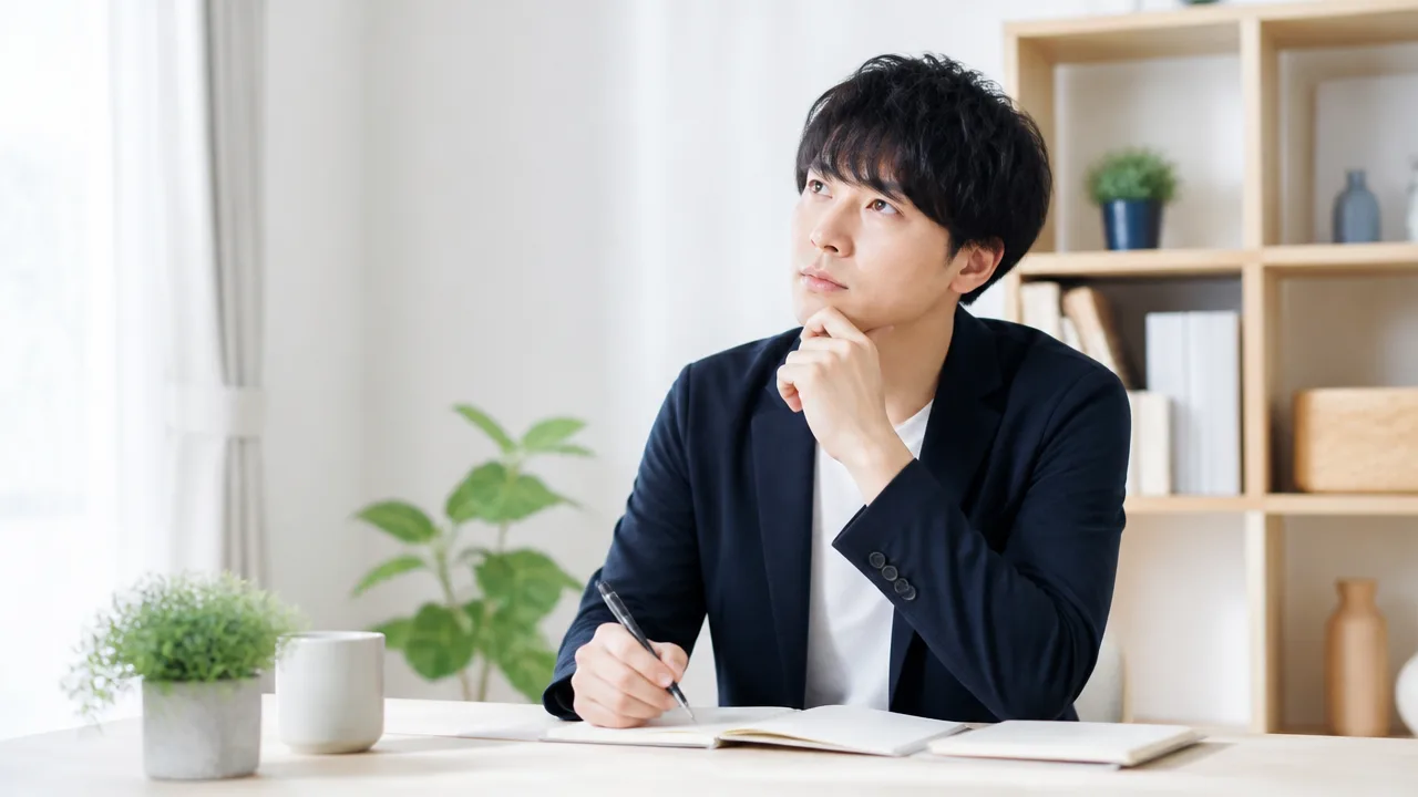 ノートとペンを前に、保証に関する書類について考える人のイメージ