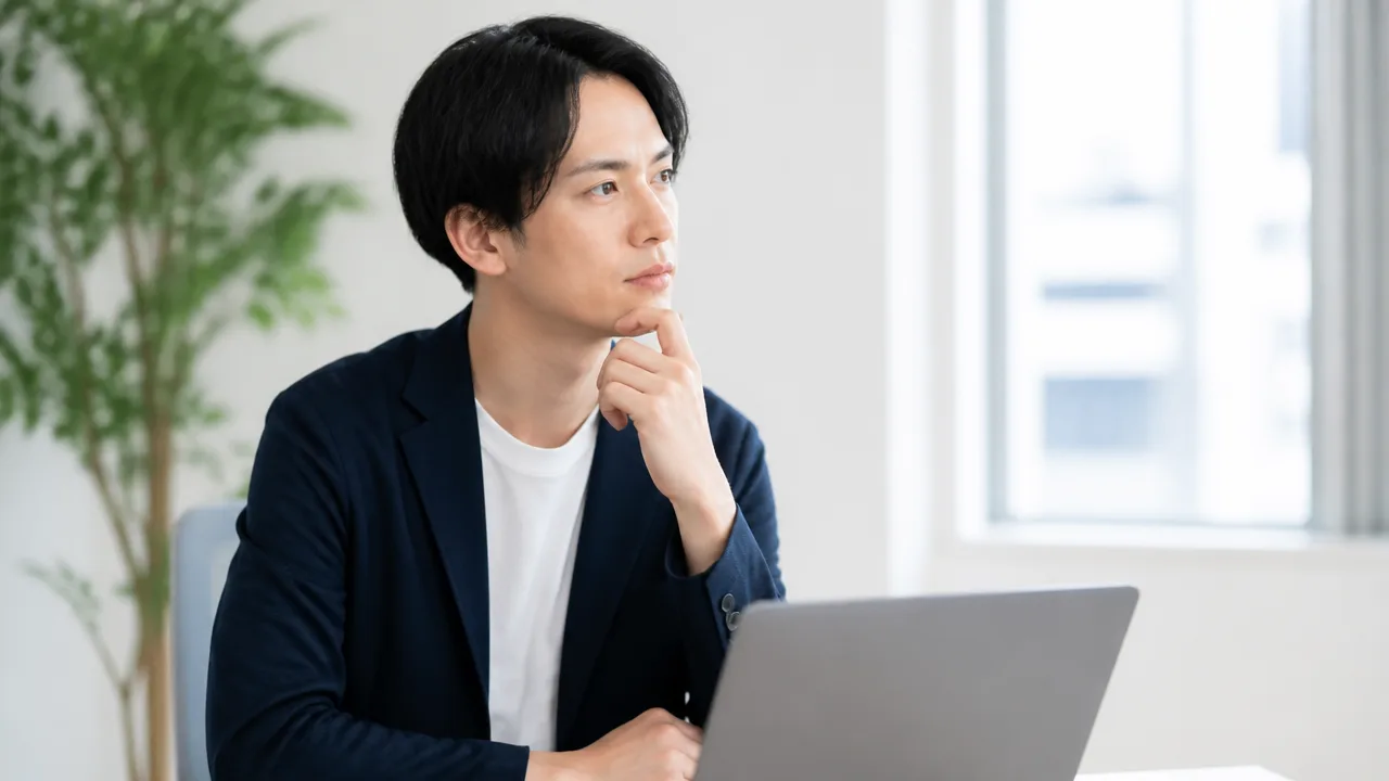 ノートパソコンの前で仕事について考える人