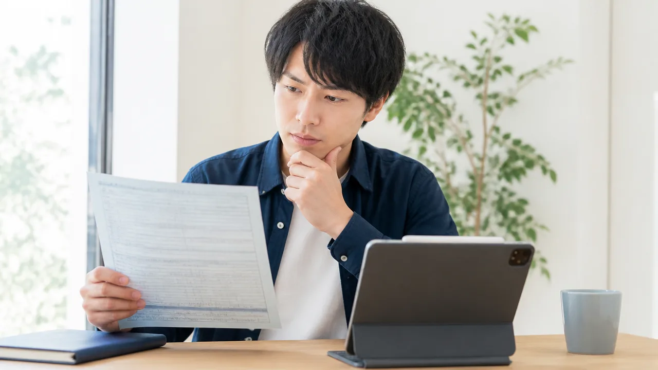 書類とタブレットを前に、情報を確認する人のイメージ